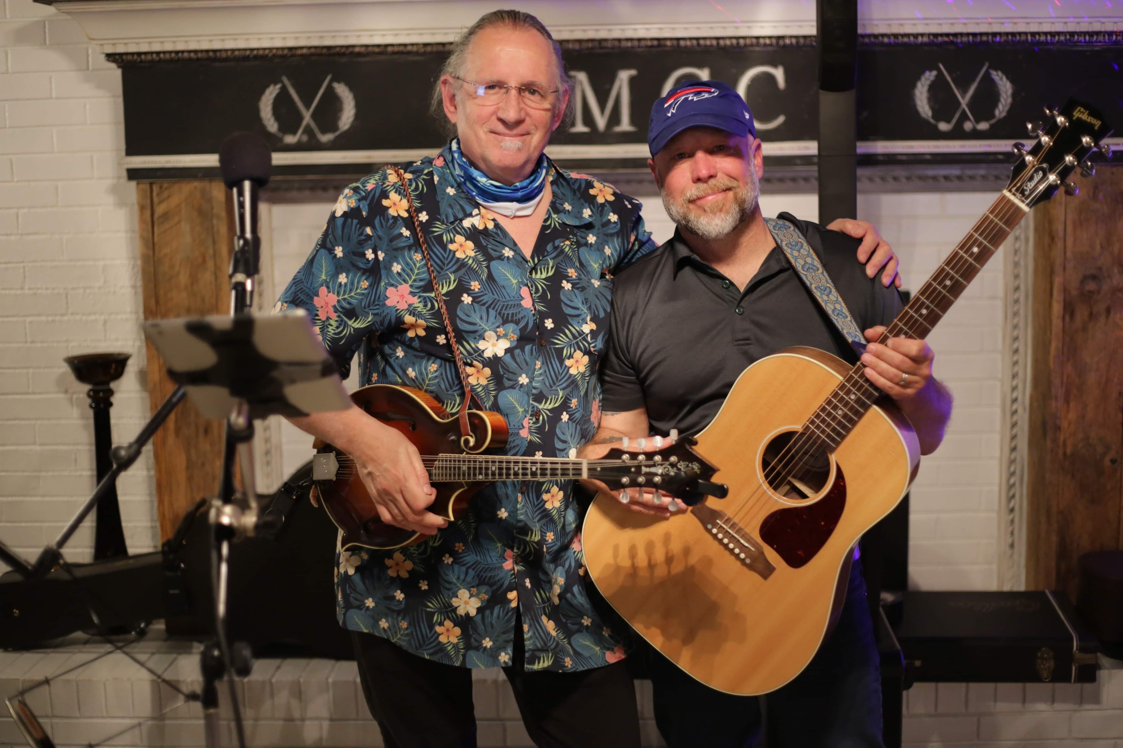 Two musicians posing with acoustic guitars